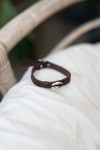 Pulsera Océano de cuero marrón con concha cauri metálica plateada y cierre de hebilla.