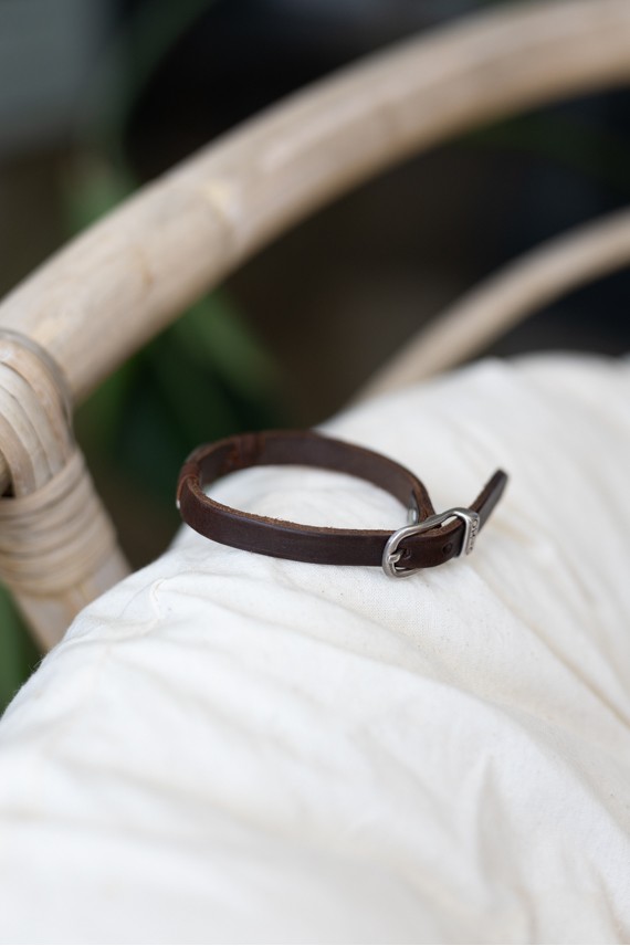 Pulsera Océano de cuero marrón con concha cauri metálica plateada y cierre de hebilla.