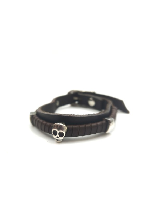 Pulsera Karma de cuero marrón con calavera metálica plateada y detalles laterales.