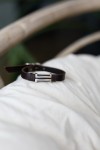 Pulsera Horizonte de cuero marrón con pieza metálica geométrica de doble línea y acabado plateado.