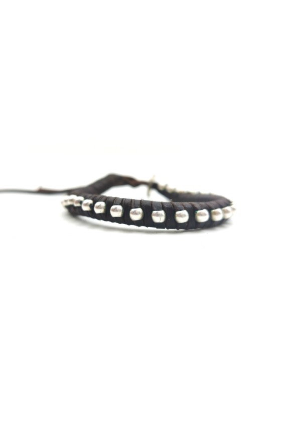 Pulsera artesanal Sol de cuero marrón con cuentas plateadas y cierre mediante cordones.