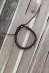 Pulsera artesanal Sol de cuero marrón con cuentas plateadas y cierre mediante cordones.