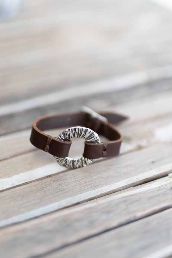 Pulsera Eclipse de cuero marrón con aro metálico circular texturizado de acabado plateado, estilo boho artesanal.