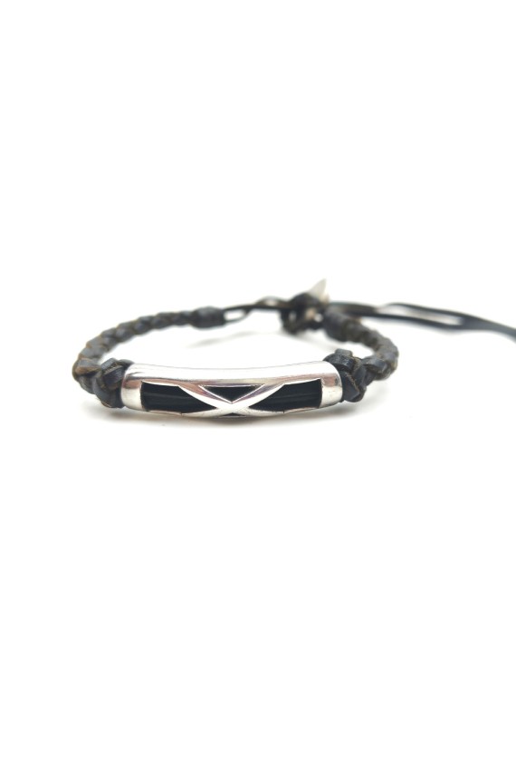 Pulsera Travesía de cuero oscuro trenzado con pieza metálica plateada y líneas entrelazadas.