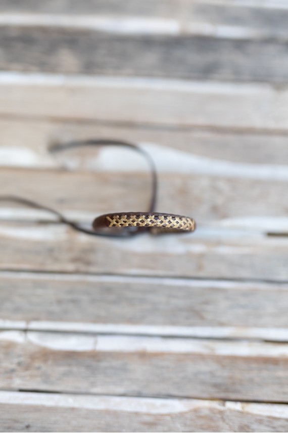 Pulsera Raíz de cuero marrón con bordado cruzado artesanal en tono natural.