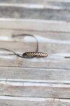 Pulsera Raíz de cuero marrón con bordado cruzado artesanal en tono natural.
