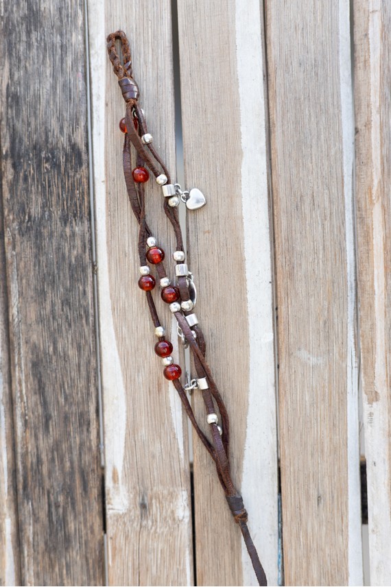 Pulsera Fuego de cuero marrón con cuentas rojas, abalorios y corazones metálicos de estilo boho.