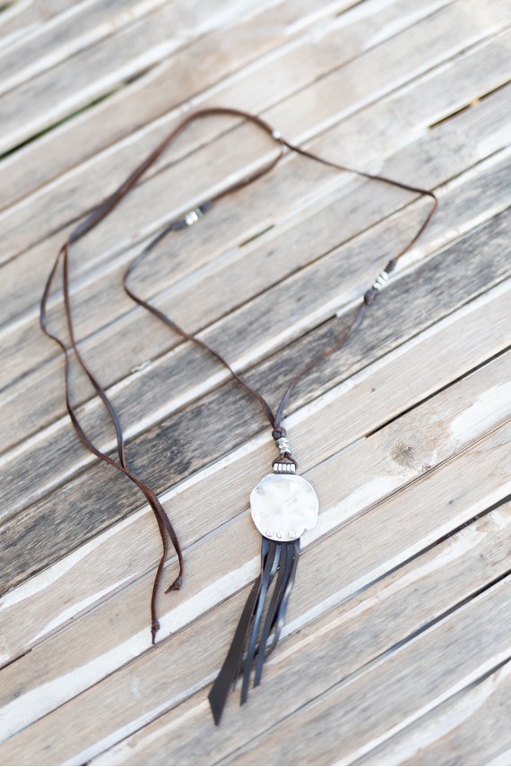 Collar artesanal de cuero con medallón circular de zamak, flecos y largo regulable estilo boho.
