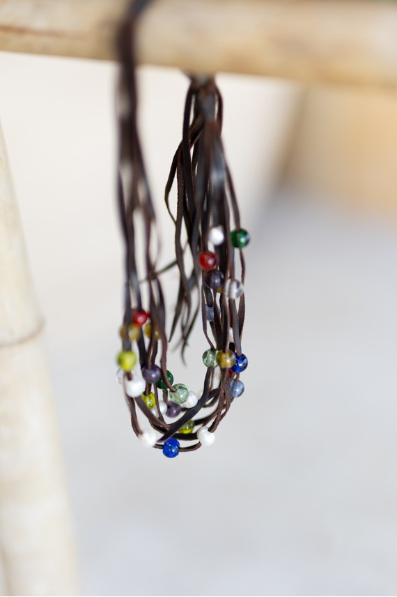 Collar boho de múltiples tiras de cuero marrón decorado con gemas multicolor.