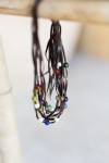 Collar boho de múltiples tiras de cuero marrón decorado con gemas multicolor.
