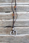 Collar boho de cuero con corazón plateado, detalles metálicos y gemas en tonos ámbar y rojizos.