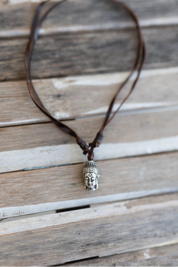 Detalle de collar de cuero con colgante cabeza de Buda de acabado metálico y diseño regulable Samarkanda.