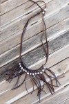 Collar de cuero hecho a mano con perlas blancas y largos flecos, diseño boho artesanal con nudo ajustable.