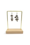 Detalle de pendientes de zamak plateado con diseños diferentes de flor en maceta y ramo floral, estilo boho vintage.
