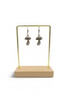 Detalle de pendientes de zamak plateado con setas tridimensionales, sombrero redondeado y tallo texturizado de estilo vintage.